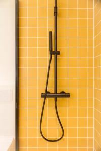a shower with a hose hanging on a yellow wall at Hopland in Antwerp