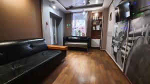 a living room with a black leather couch and a table at Hostel Happy House в центре in Izhevsk
