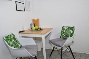 ein Zimmer mit einem Tisch und zwei Stühlen sowie einem Tisch mit Äpfeln darauf in der Unterkunft N37 -modern eingerichtete Zimmer in ruhiger Lage in Aldingen