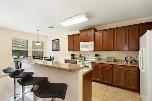 a kitchen with wooden cabinets and a large island with bar stools at Family Friendly - South Facing Pool - Game Room - Gated - Near Disney in Davenport