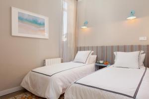 2 Betten in einem Zimmer mit weißen Wänden in der Unterkunft My Address on the Beach and Sun in Barcelona