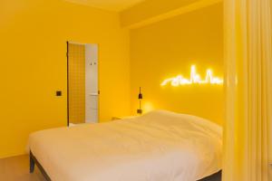 Dormitorio amarillo con cama y luces en la pared en Hopland, en Amberes