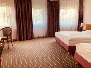 a hotel room with two beds and a chair at Akzent Congresshotel Hoyerswerda in Hoyerswerda