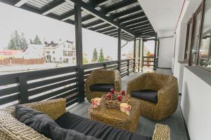 a balcony with wicker chairs and a table at Anda Apartment in Azuga