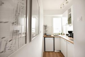 a white kitchen with white cabinets and a wooden floor at WHITE HAVEN - Calea Victoriei Studio in Bucharest