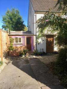 a white house with a purple door and a fence at Cute self-contained guest room with ensuite and private decked porch in Glastonbury in Glastonbury