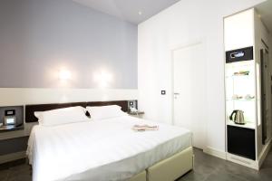 a bedroom with a white bed and a refrigerator at Crosti Hotel in Rome