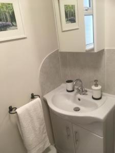 a white bathroom with a sink and a mirror at Cute self-contained guest room with ensuite and private decked porch in Glastonbury in Glastonbury