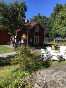 a red barn with white chairs and a house at Notholmen, Tyresö in Tyresö