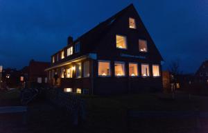 una casa iluminada por la noche con luces en las ventanas en Gästehaus am Deich, en Juist
