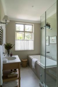 a bathroom with a tub and a sink and a shower at Cape Vue Country House in Franschhoek