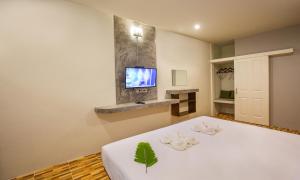 a bedroom with a white bed with a tv on the wall at Phangnga Keeree Resort & Gallery in Phang-nga