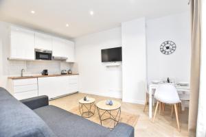 een woonkamer met een grijze bank en een keuken bij Appartement qui touche casiment la Bastille ! in Parijs