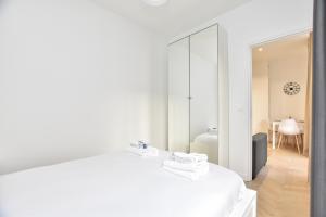 a bedroom with a white bed and a mirror at Appartement qui touche casiment la Bastille ! in Paris