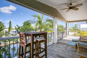 a screened porch with a table and chairs and a ceiling fan at Cayo Loco in Little Torch Key