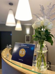 una mesa con un jarrón de rosas blancas y una tarjeta en Hotel Eva, en Perm