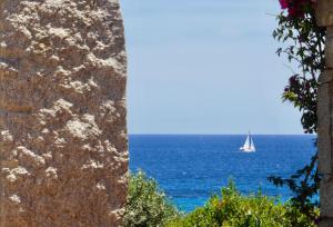 a sailboat in the ocean seen through a window at BGItalianVacation - Ville di Rocca Sant'Elmo in Castiadas