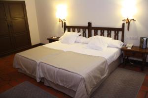 1 dormitorio con 1 cama grande con sábanas y almohadas blancas en Parador de Ávila, en Ávila