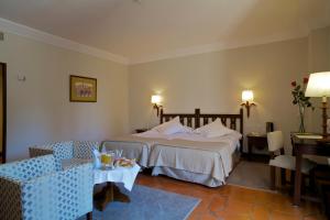 a hotel room with a bed and a table and chairs at Parador de Ávila in Ávila