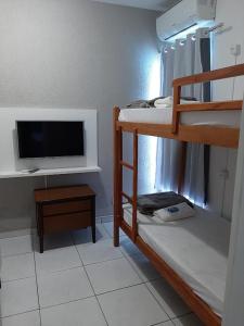 a small room with a bunk bed and a tv at Hostel Maré Mansa in Cabo Frio