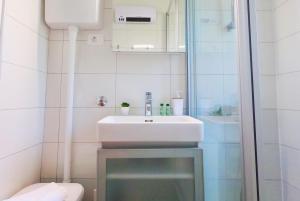 a white bathroom with a sink and a shower at Beachfront Apartment Mala Tereza in Split