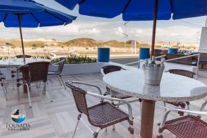 patio ze stołami i krzesłami z niebieskimi parasolami w obiekcie Pousada Ilha dos Lobos w mieście Torres