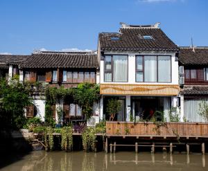 a row of houses on the water next to a river at 同里泊·晓烟河景民宿 in Suzhou