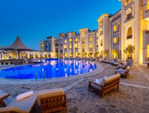 a hotel with a large swimming pool in front of a building at Ezdan Palace Hotel in Doha
