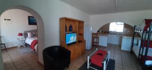 a room with a kitchen and a living room with a television at Oom Piet Accommodation in Gansbaai