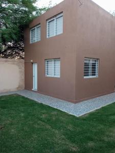 a brown house with windows and a grass yard at Duplex Chacabuco in San Fernando del Valle de Catamarca