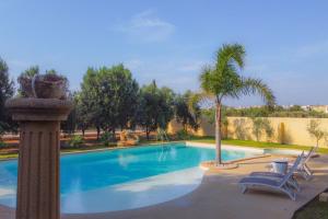 una piscina con due sedie e una palma di Villa Matilde - Xenia Sicily Villas a Mazara del Vallo