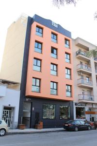 Un bâtiment orange avec une voiture garée devant. dans l'établissement Hotel Ciutat d'Amposta, à Amposta