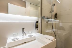 a white bathroom with a sink and a shower at Hotel My Way Zürich Wallisellen in Wallisellen