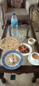 a coffee table with plates of food and a bottle of water at Executive Galaxy Guest House in Islamabad