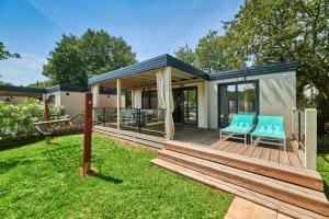 a house with a deck with two chairs on it at Camping Stella Maris Mobile Homes in Umag