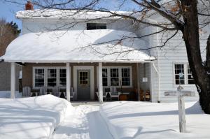 una casa blanca con nieve en el porche en Tornado's Motel, en Port Loring