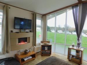 a living room with a fireplace and large windows at Dyfed 23 in Borth
