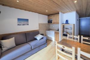 a living room with a couch and a kitchen at Résidence Aiguille Lodge in Les Deux Alpes
