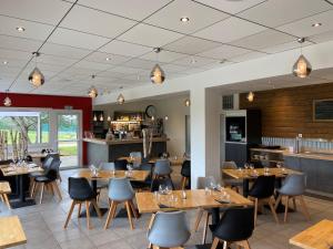 a restaurant with wooden tables and chairs and a bar at Logis Cris Hôtel et Restaurant, Lyon Sud-Est in Corbas