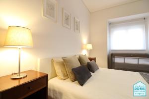 a bedroom with a bed with a lamp and a window at Chez Nous - Guest House in Barreiro