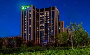 乌鲁木齐Holiday Inn Express Urumqi Station by IHG的晚上，建筑物顶部有标志