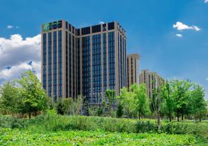乌鲁木齐Holiday Inn Express Urumqi Station by IHG的前面有树木的高楼