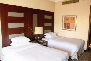 two beds in a hotel room with white sheets at Al Corniche in Jeddah