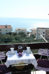 einen Tisch mit einem Tee-Set auf einem Balkon mit Meerblick in der Unterkunft Apartments Petrada in Omiš