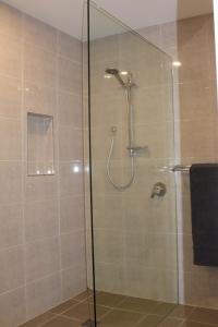 une douche avec une porte vitrée dans une salle de bain dans l'établissement Ayada Villa - Pet Friendly - 1 Min to Beach, à Culburra Beach