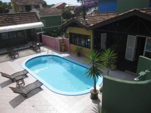 a swimming pool on a patio with chairs and a house at Pousada Vento Sul in Florianópolis