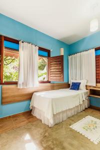 a bedroom with a bed with blue walls and windows at Pousada Riacho dos Milagres in São Miguel dos Milagres