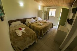 two beds in a hotel room with towels on them at Pousada Flor de Noronha in Fernando de Noronha