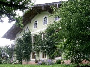 una grande casa verde con alberi di fronte di Sprenghof a Breitbrunn am Chiemsee
