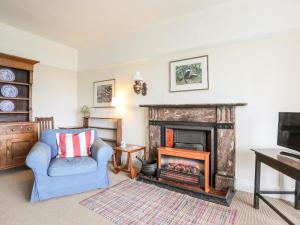 a living room with a fireplace and a blue chair at Windygates in Rhosneigr